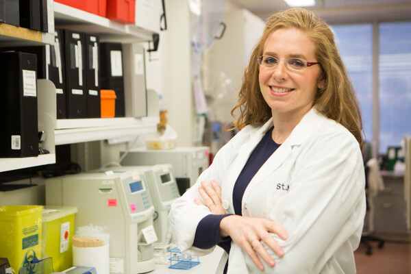 Dr. Michelle Sholzberg standing with arms crossed smiling in a lab