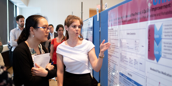 Trainee present a poster to a faculty member