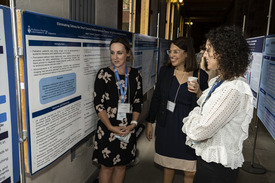 Image of three physicians examining a research poster, in discussion with one another 