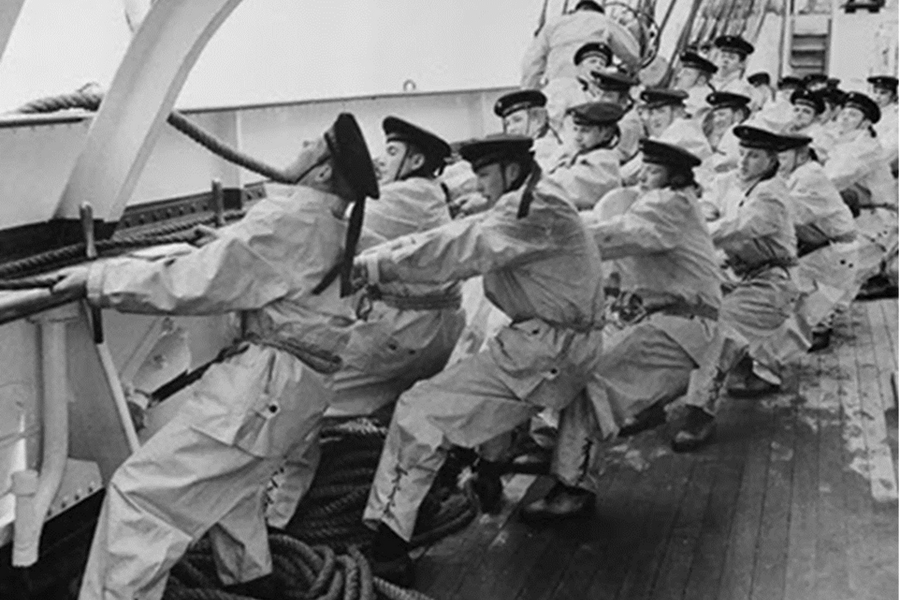 Black and white photo of several sailors pulling on a rope