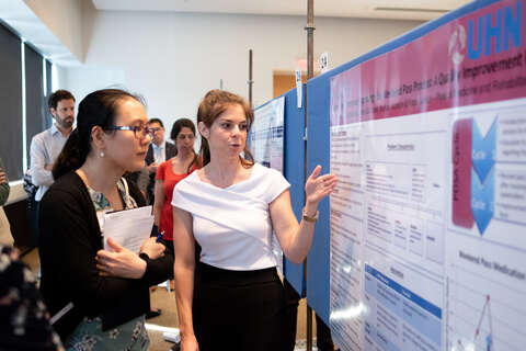 Trainee present a poster to a faculty member