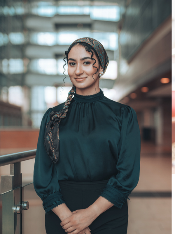 Woman with light brown skin and a scarf tied over her hair