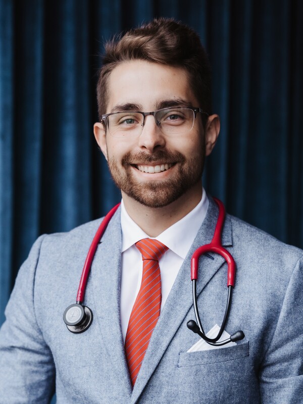man wearing grey blazer and red tie, red stethoscope