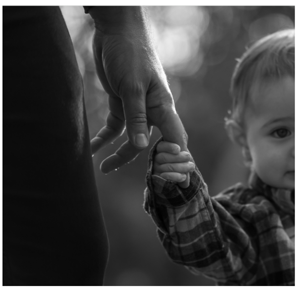 Black and white photo of an adult holding a child's hand