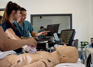 Faculty and learners practicing on a simulation manikin in an emergency medicine environment