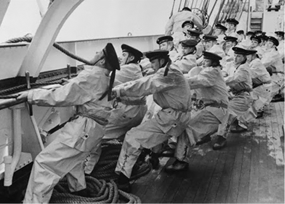 Black and white photo of several sailors pulling on a rope